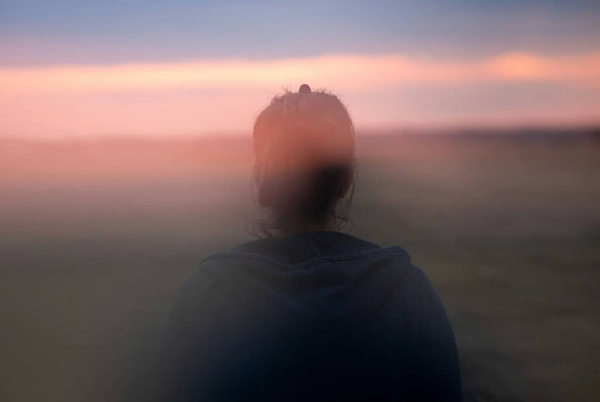 Rückführungstherapie – inneres Erleben Person von hinten in unscharfer Landschaft – nach innen gerichteter Moment